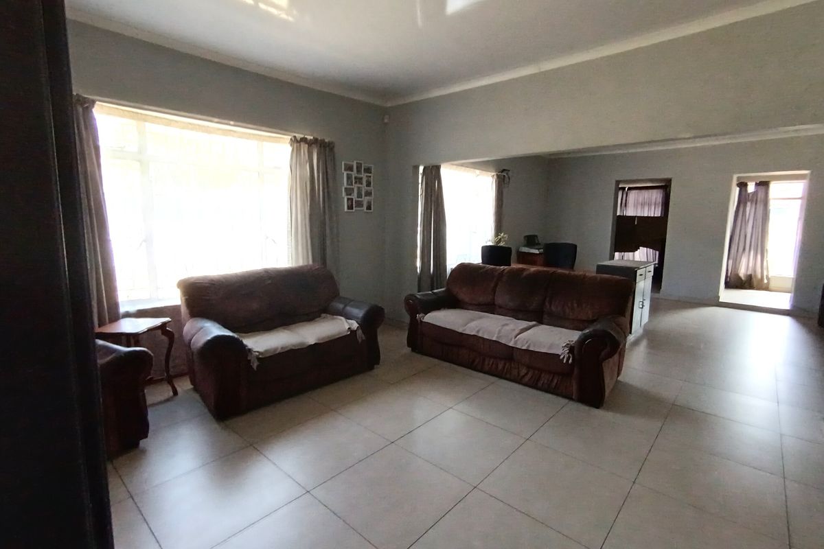 Spacious living area featuring large windows for natural light and neutral tiled flooring, offering a versatile layout for comfortable family living.