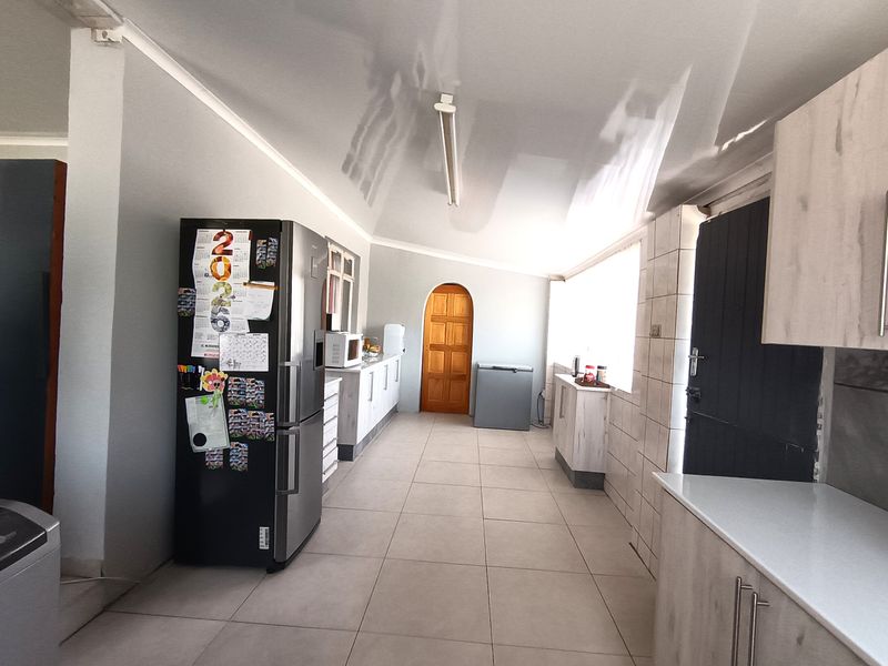 A functional kitchen space featuring tiled flooring, built-in cabinetry, and an arched doorway, offering a practical layout with potential for cosmetic updates.
