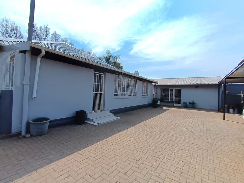 A spacious paved rear courtyard area featuring a low-maintenance exterior, security-fitted windows and doors, and an attached carport structure.