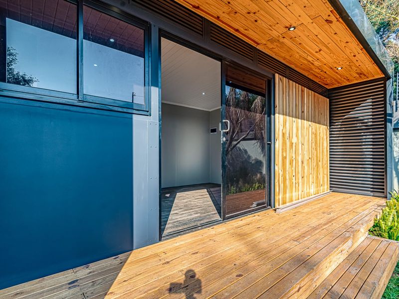 A modern outdoor timber deck featuring recessed lighting and a sliding glass door entrance to the interior space.