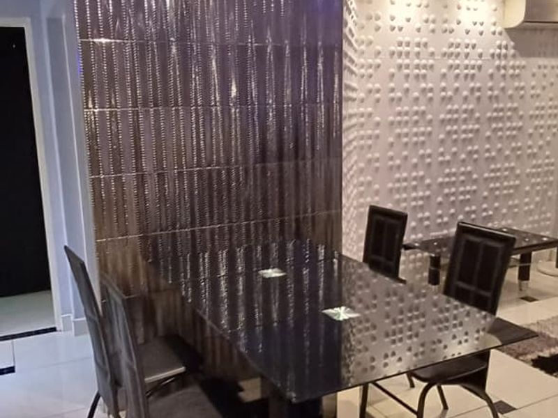 Dining area featuring glossy tiled floors, a textured feature wall, and modern recessed downlighting with ambient cove lighting.