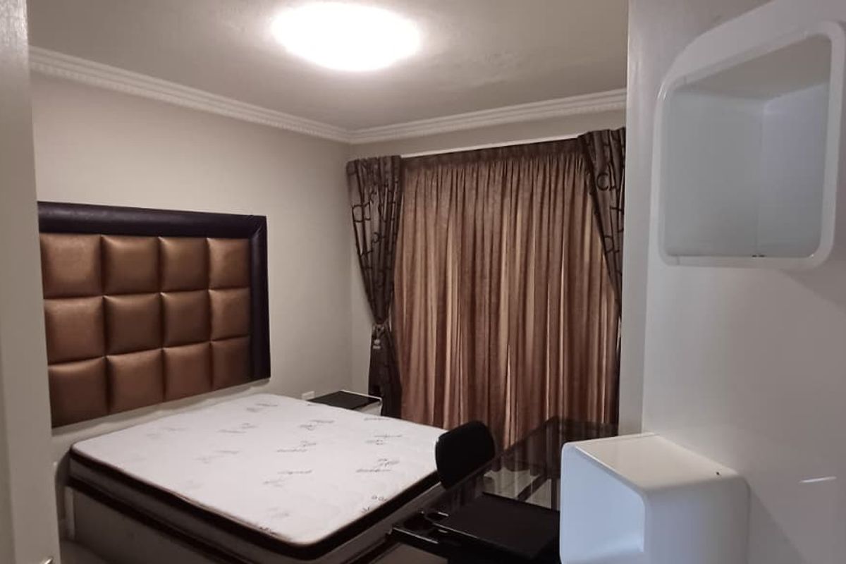 A well-maintained bedroom featuring crown molding and built-in wall shelving, providing a clean and functional living space.