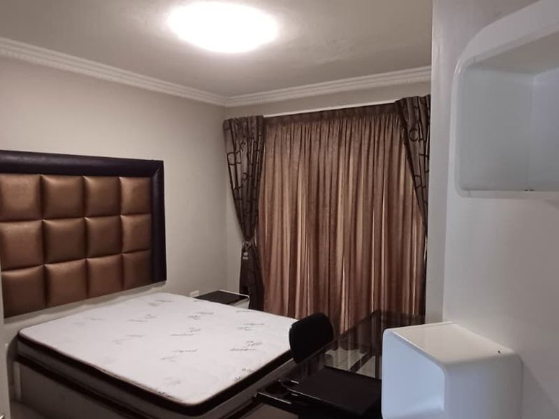 A well-maintained bedroom featuring crown molding and built-in wall shelving, providing a clean and functional living space.