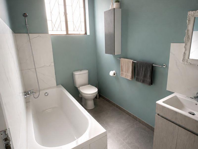 Modern bathroom featuring a bathtub with shower mixer, vanity cabinet with washbasin, toilet, and stylish timber ceiling finishes.
