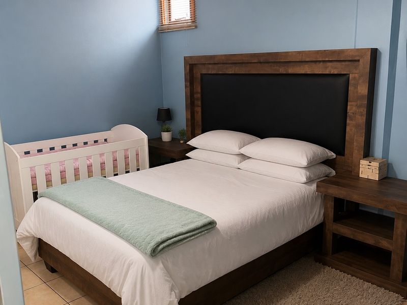 A bedroom featuring ceramic floor tiles, a timber-paneled ceiling, and a small casement window, providing a functional and cozy sleeping space.