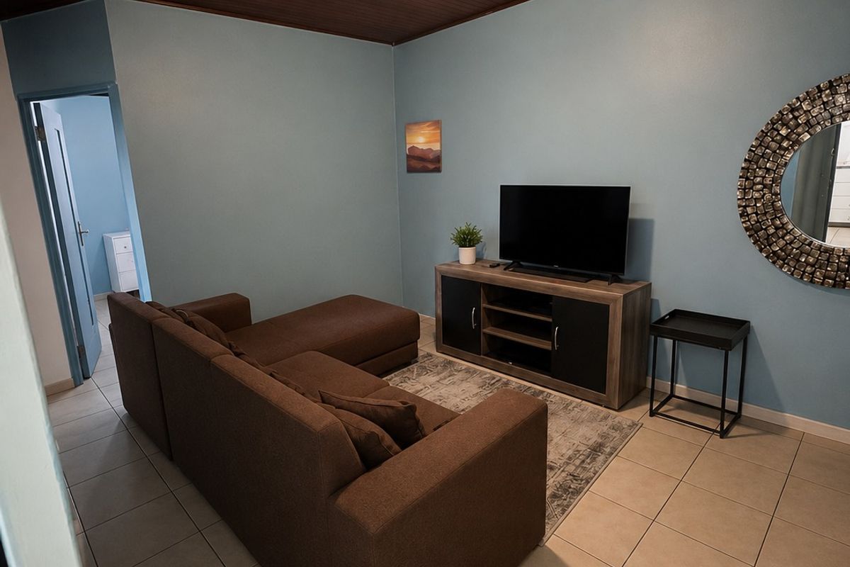 A living room featuring a distinctive timber-clad ceiling, neutral ceramic floor tiles, and light blue painted walls.