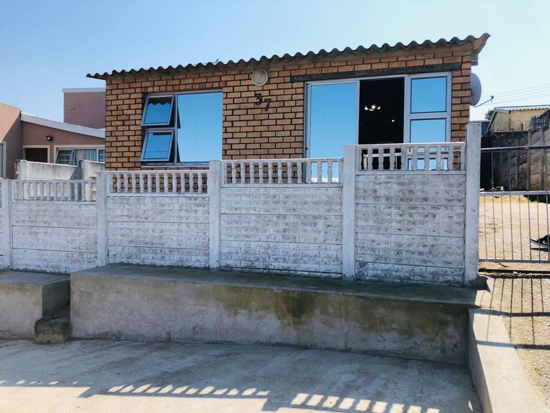 Front exterior view of a face brick house featuring aluminium windows, a sliding door, and a precast concrete boundary wall.
