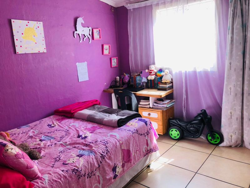 A bedroom featuring tiled flooring and a window with a curtain rail, currently decorated with vibrant purple wall paint.