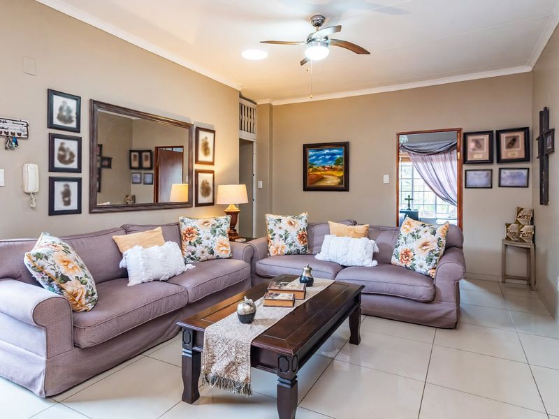 A well-maintained living room featuring neutral wall tones, large format floor tiles, and a central ceiling fan, providing a comfortable and inviting space.
