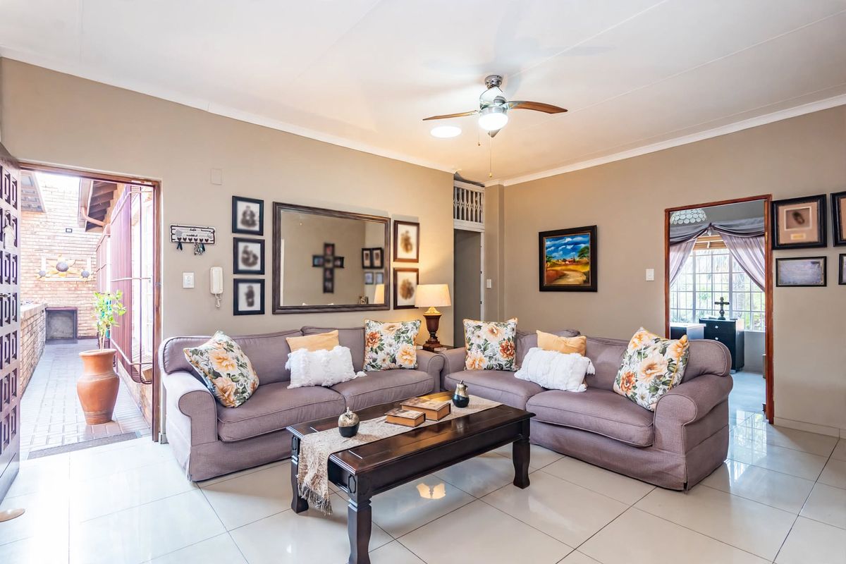 A well-maintained living room featuring neutral tiled flooring, a ceiling fan, and direct access to an outdoor patio area.
