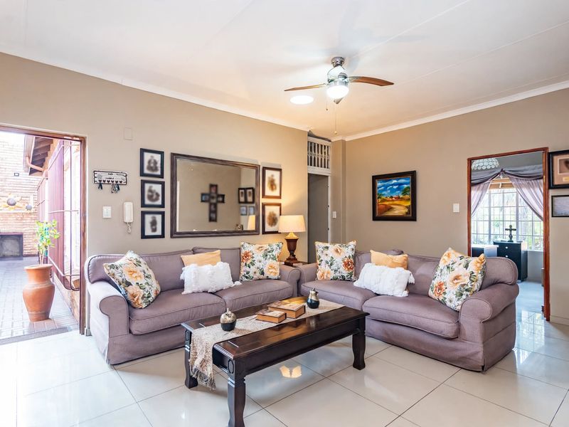 A well-maintained living room featuring neutral tiled flooring, a ceiling fan, and direct access to an outdoor patio area.