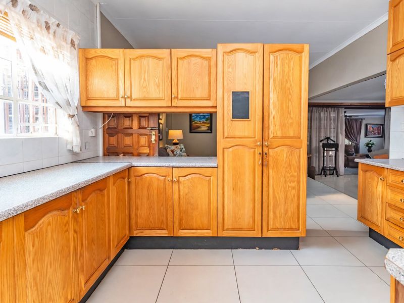 A functional kitchen featuring traditional wooden cabinetry, laminate countertops, and tiled flooring, offering a classic layout with potential for modern updates.