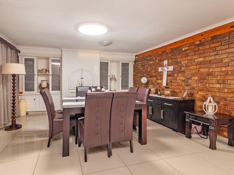 A dining room featuring an exposed brick feature wall, tiled flooring, and built-in white cabinetry.