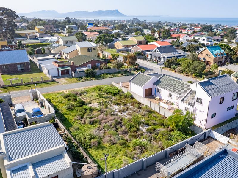 Aerial view of a vacant residential plot situated in a developed coastal neighborhood, featuring established boundary fencing and surrounding residential infrastructure.