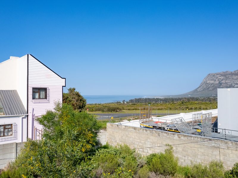 A scenic elevated view overlooking the coastal landscape, surrounding vegetation, and distant mountain range.