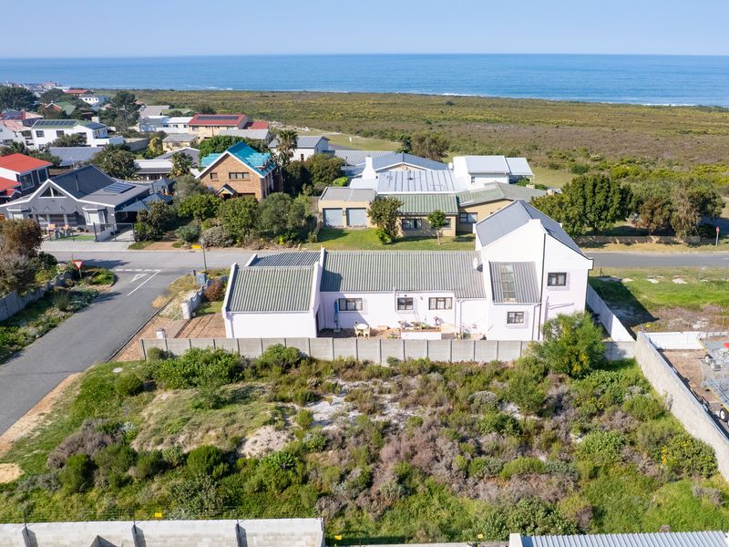 Aerial view of a residential property featuring a vacant plot with natural vegetation, enclosed by precast concrete walls and electric fencing.