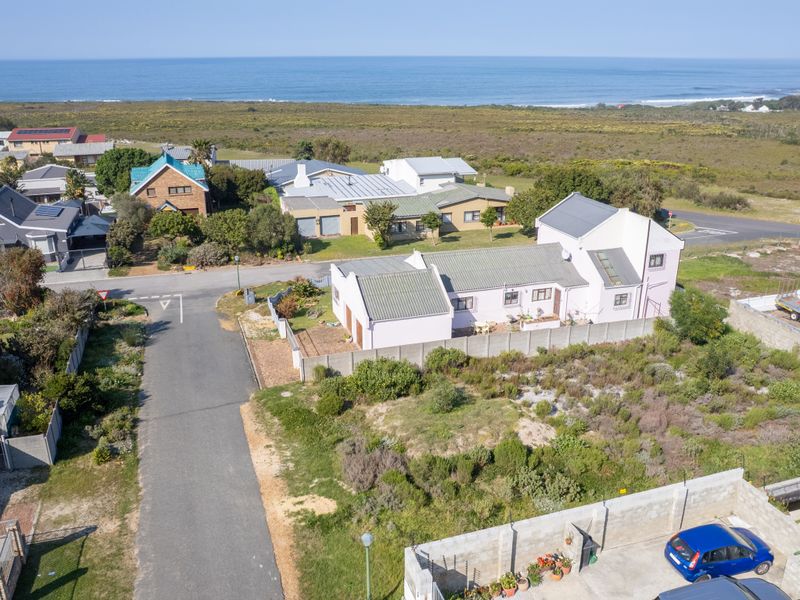 Aerial view of a residential property and surrounding neighborhood, showcasing the coastal location and proximity to the ocean.