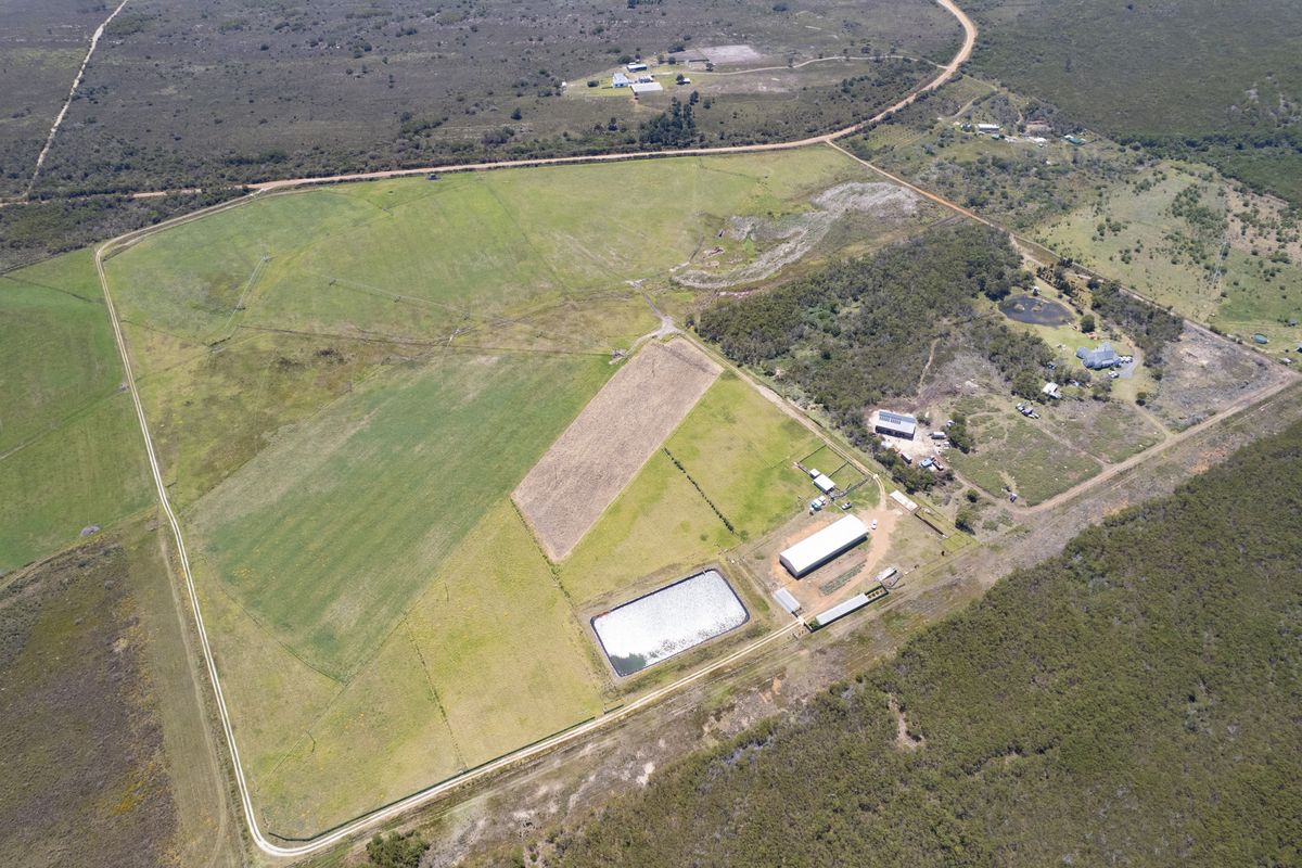 Aerial view of a large residential vacant land plot featuring open grazing fields, a farm dam, and existing outbuildings.
