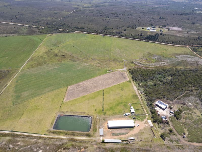 Aerial view of a large vacant residential land parcel featuring a farm dam, large shed, and established fencing.
