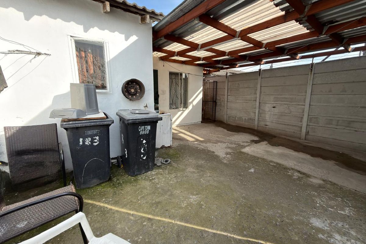 A paved rear courtyard area featuring a timber pergola structure and precast concrete boundary walling, providing a functional outdoor utility space.