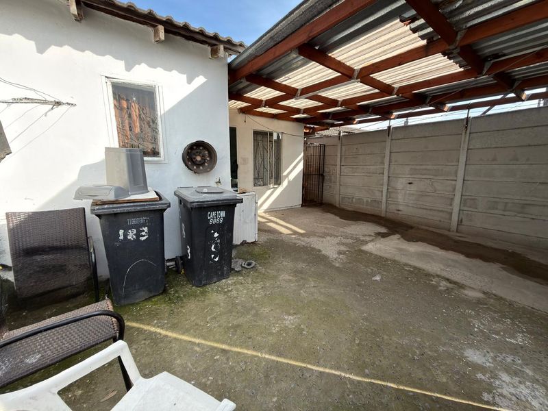 A paved rear courtyard area featuring a timber pergola structure and precast concrete boundary walling, providing a functional outdoor utility space.