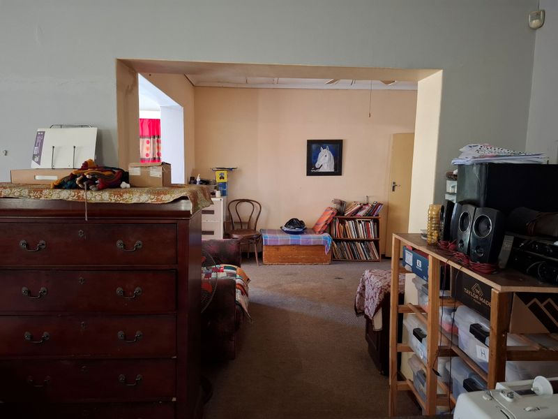 A living area featuring an open archway leading to an adjacent room, with carpeted flooring and neutral wall finishes.