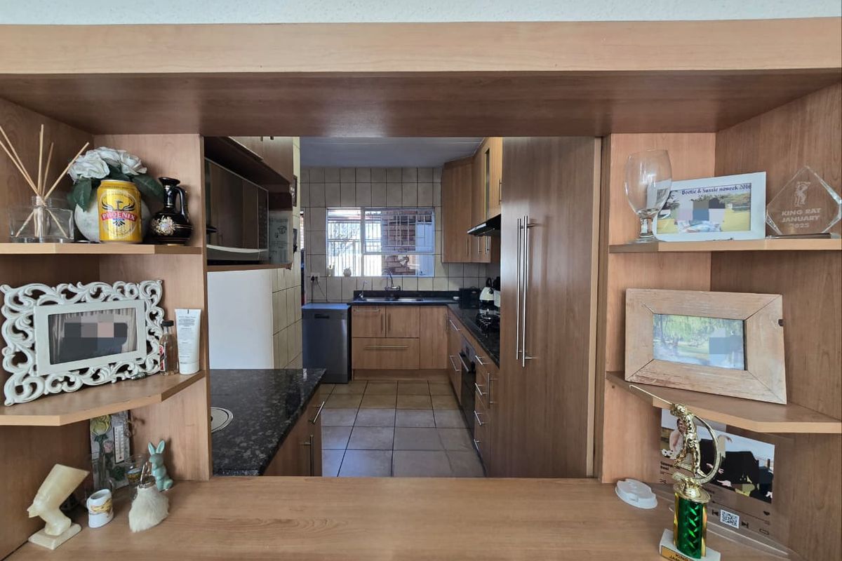 A functional kitchen featuring wooden cabinetry, granite countertops, and a convenient pass-through window connecting to the adjacent living area.