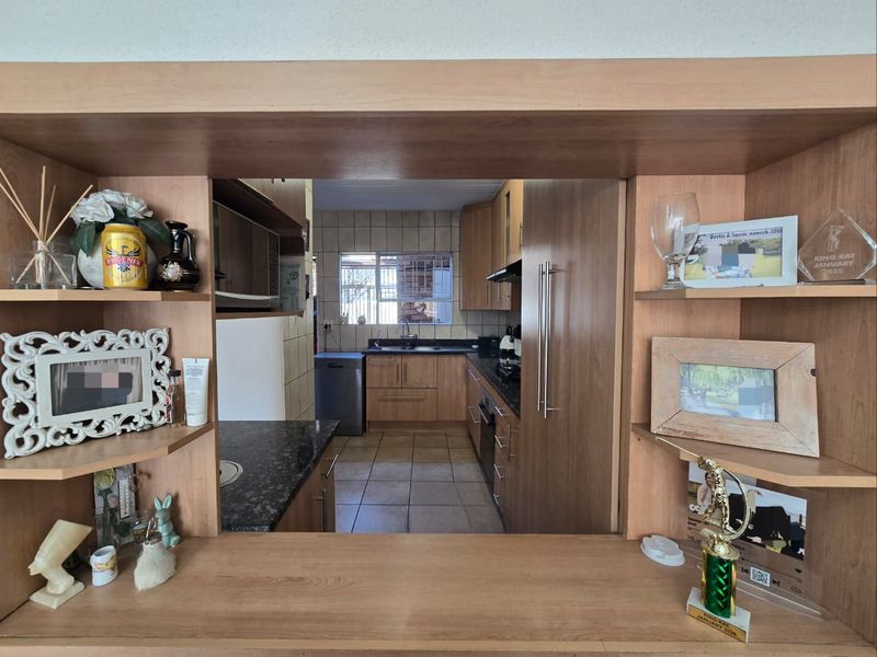 A functional kitchen featuring wooden cabinetry, granite countertops, and a convenient pass-through window connecting to the adjacent living area.