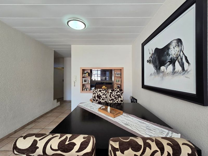 Dining area featuring tiled flooring, a pass-through window to the kitchen, and a flush mount ceiling light.