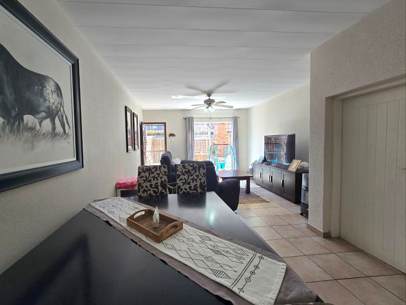 Open-plan living and dining area featuring tiled flooring, a ceiling fan, and direct access to the outdoor space through a sliding glass door.