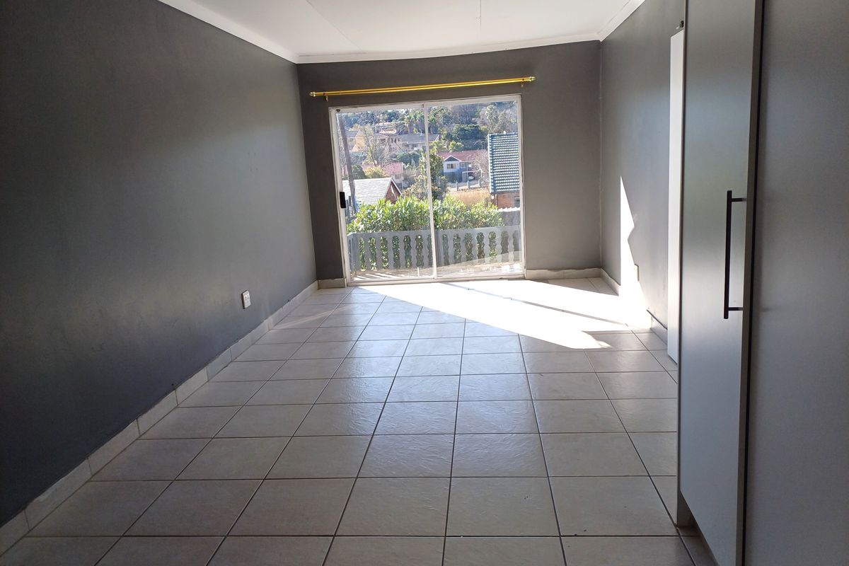 An empty bedroom featuring tiled flooring, a built-in cupboard, and a sliding glass door providing access to an outdoor area.