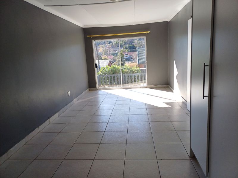 An empty bedroom featuring tiled flooring, a built-in cupboard, and a sliding glass door providing access to an outdoor area.