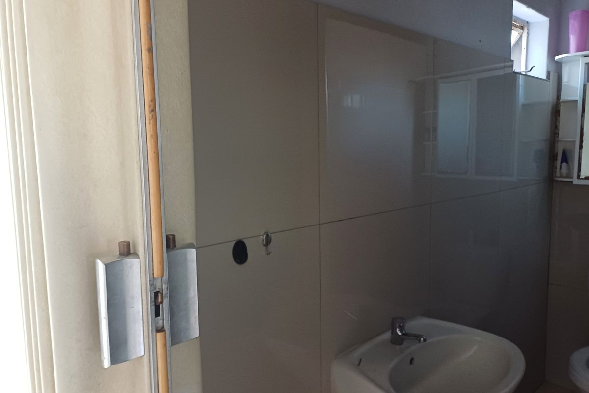 A compact bathroom featuring a wall-mounted basin with a mixer tap and tiled wall finishes.