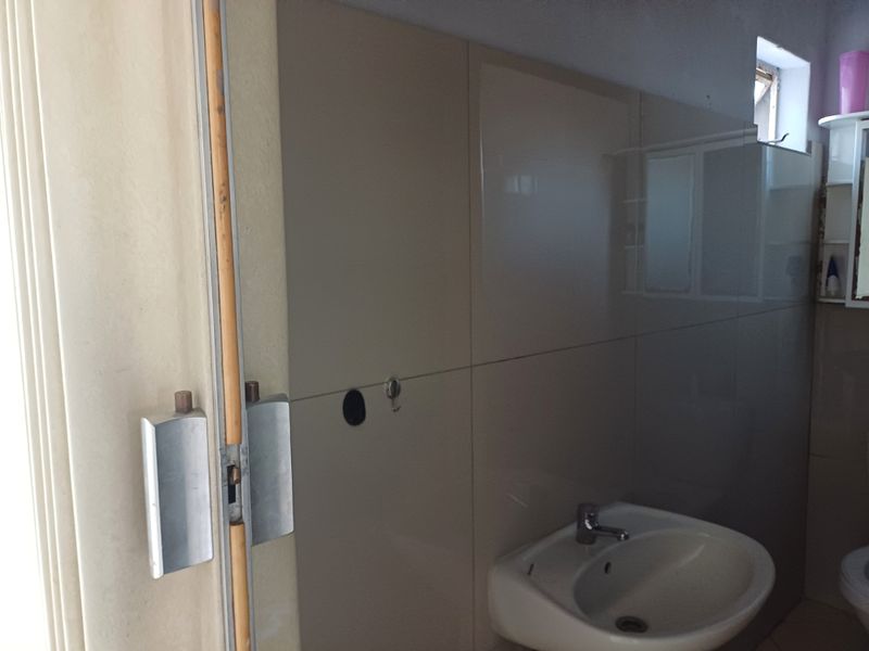 A compact bathroom featuring a wall-mounted basin with a mixer tap and tiled wall finishes.