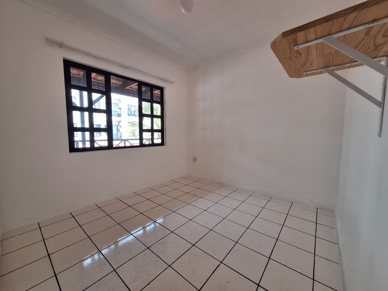 A bright, empty bedroom featuring white walls, tiled flooring, and a grid-pattern window, providing a clean canvas for personalization.