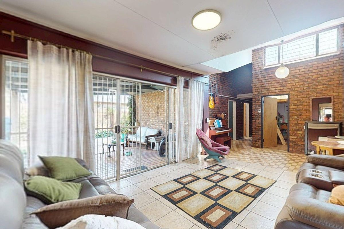 Spacious living area featuring exposed brick walls, tiled flooring, a skylight, and large sliding glass doors providing access to the outdoor patio.
