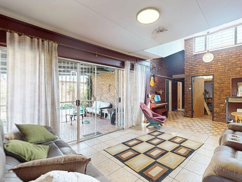 Spacious living area featuring exposed brick walls, tiled flooring, a skylight, and large sliding glass doors providing access to the outdoor patio.