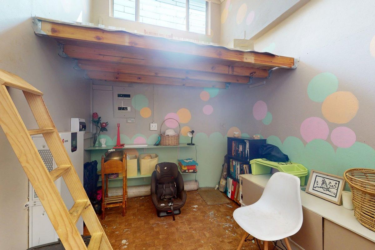 A bedroom featuring a mezzanine loft level accessed by a wooden ladder, high-level window, and electrical distribution board.