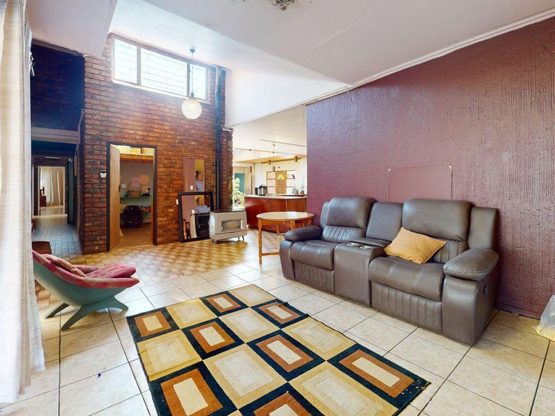 Spacious open-plan living area featuring exposed brick walls, high ceilings with clerestory windows, and tiled flooring, offering a unique architectural layout.