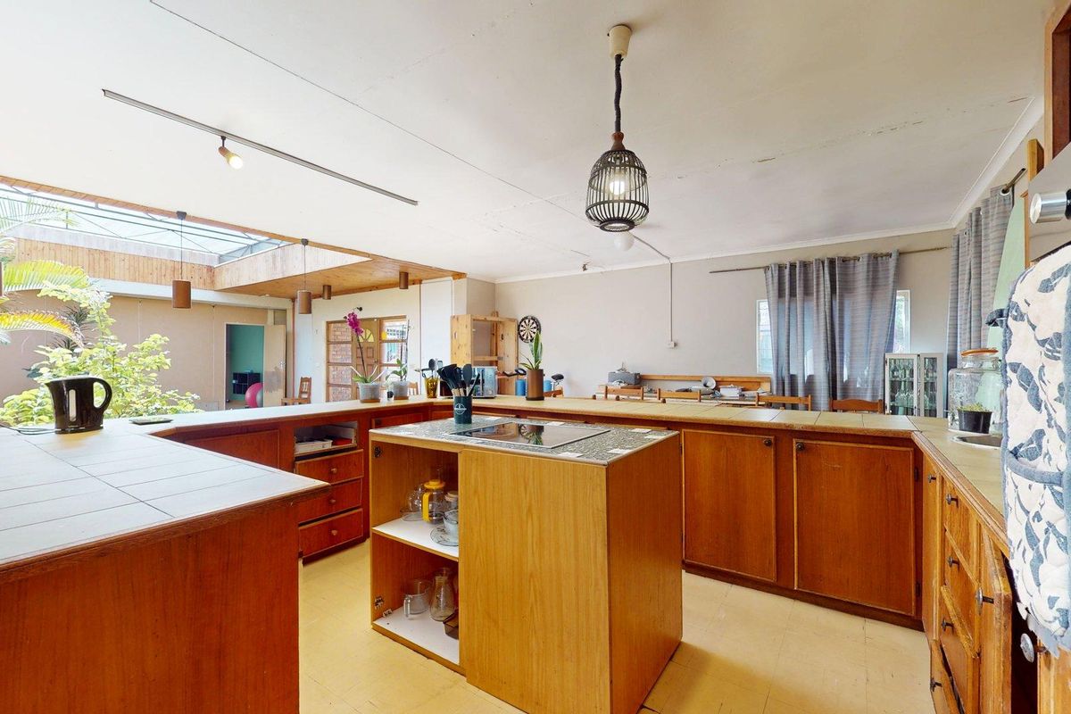 Spacious kitchen featuring extensive wooden cabinetry, tiled countertops, a central island with a hob, and a large skylight providing natural light.