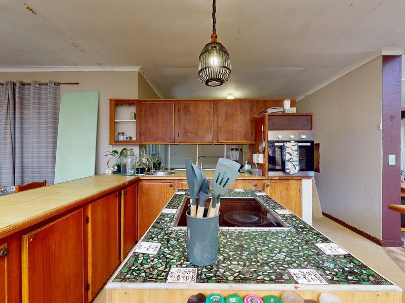 A dated kitchen featuring wooden cabinetry, a built-in oven, and a unique tiled island countertop with an integrated electric cooktop.