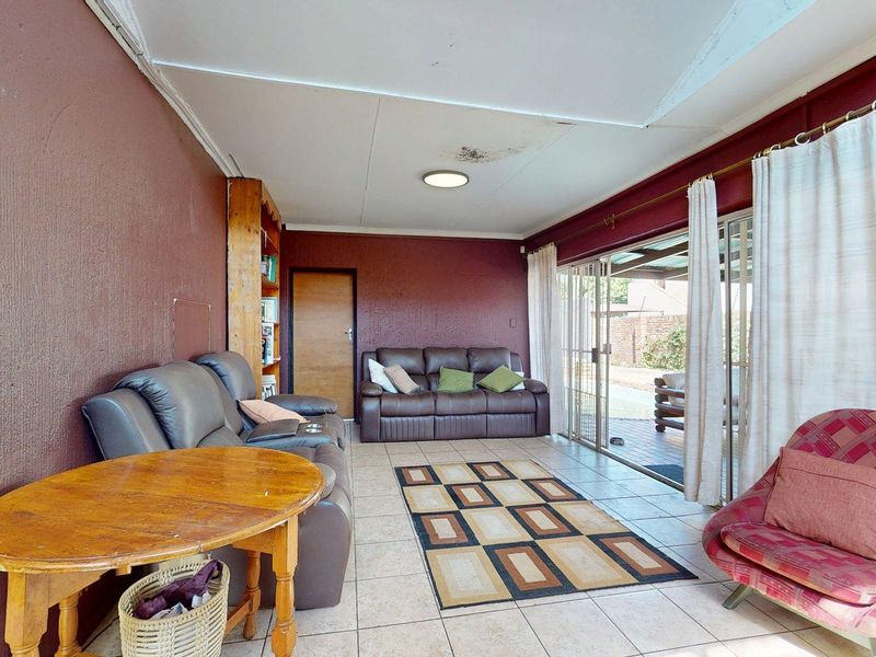 Living room featuring tiled flooring and sliding glass doors leading to the patio, with visible ceiling water damage requiring repair.