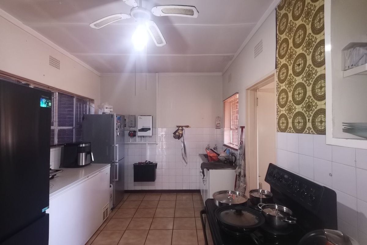 A functional kitchen featuring tiled flooring, a tiled splashback, and built-in cabinetry, offering a practical layout with potential for modern updates.