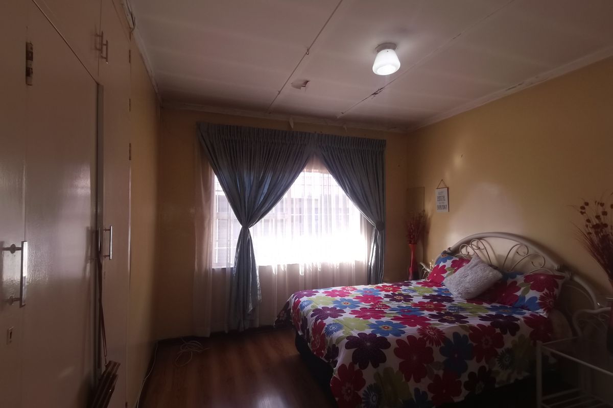 A bedroom featuring laminate flooring and built-in cupboards, requiring some ceiling repairs to improve the overall condition of the space.