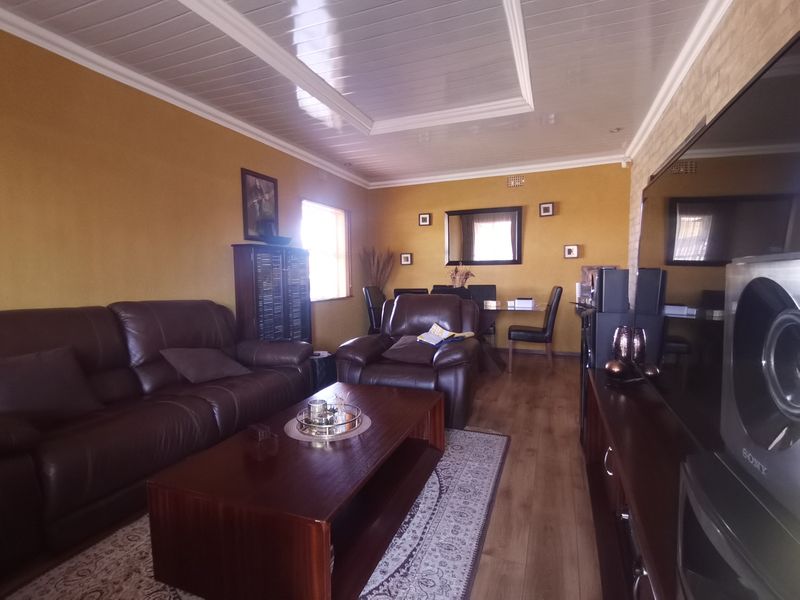 A comfortable living room featuring laminate flooring and a glossy panelled ceiling with coving, providing a functional and lived-in space.