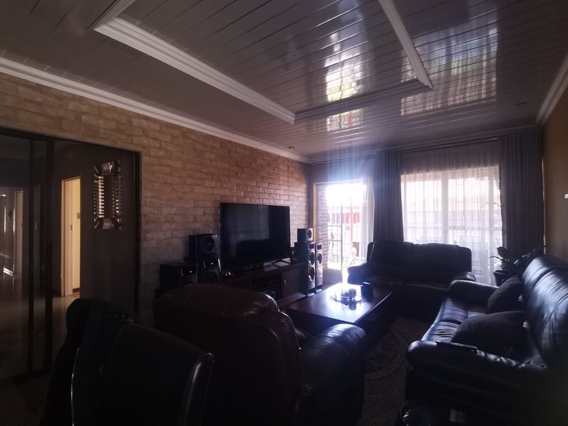 A living room featuring an exposed brick wall, glossy ceiling panels, and direct access to an outdoor area through a sliding glass door.