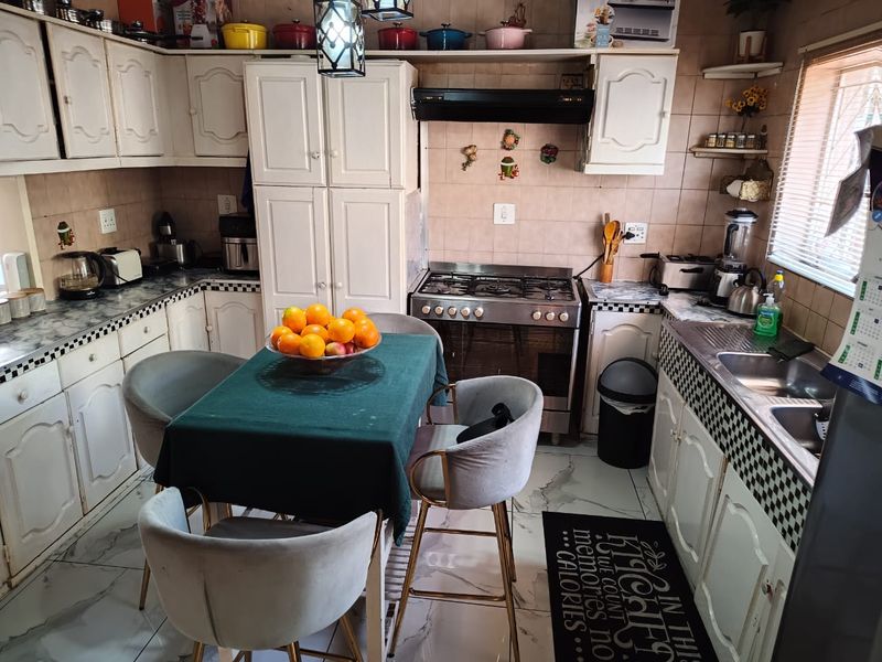 A functional kitchen featuring white cabinetry, a gas stove with extractor fan, double basin sink, and tiled backsplash with marble-look flooring.