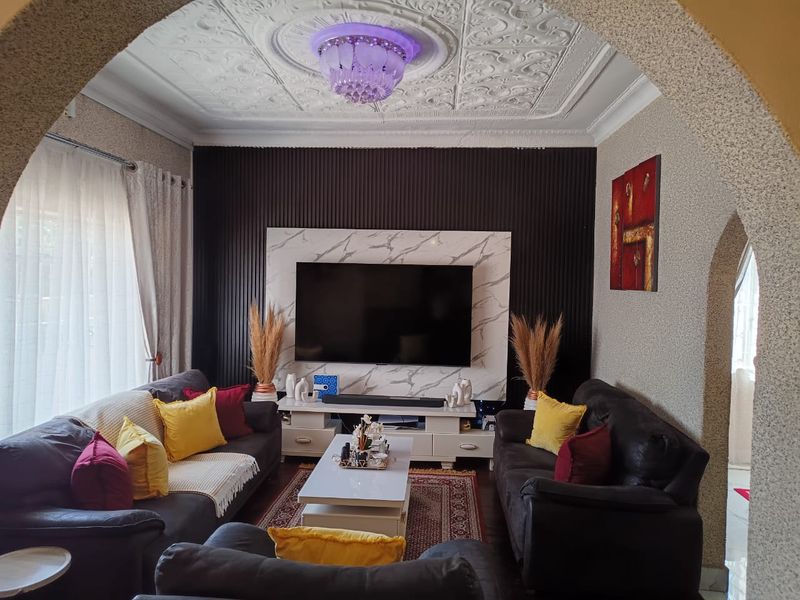 A cozy living room featuring an ornate plaster ceiling, a modern marble-look feature wall, and a distinctive arched entryway.