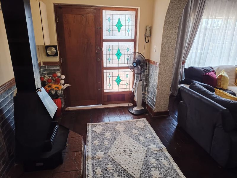 Living room featuring a freestanding fireplace with tiled hearth, timber flooring, and a characterful stained glass front door entrance.
