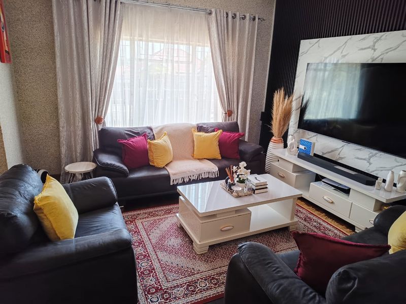 A well-maintained living room featuring a modern marble-look media wall panel and a textured feature wall.
